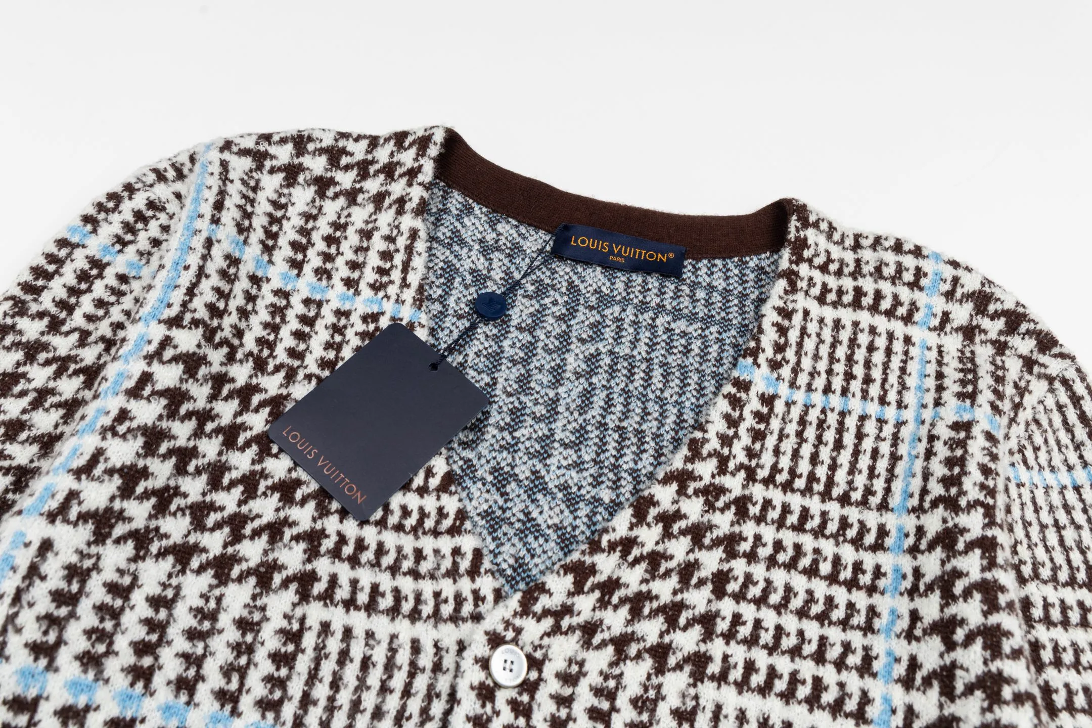 🅿️570 1v 26SS houndstooth letter intarsia V-neck knitted cardigan. The original version was purchased for 14,743 and developed. The fabric is made of yarn fabric made of 69% sheep wool blended with 31% nylon. The main pattern is woven with a full-width jacquard process, which interweaves the houndstooth pattern with light blue line texture. At the same time, the brand logo elements are integrated into the body through the intarsia process, and the edges of the pattern are connected delicately and seamlessly. The collar, cuffs and hem are made of 100% sheep wool ribbed fabric, and are edged with double-needle seaming technology, which has both elasticity and shaping effect. The front placket is equipped with natural-textured buttons, and the side seam pockets use invisible stitching technology to blend naturally with the jacquard texture of the body. The overall shape is shaped through three-dimensional tailoring, and the shoulders are stitched with seamless stitching to ensure fit and comfort. The entire piece is finished with handcrafted details in an Italian workshop, showing the craftsmanship precision of high-quality knitted items. The overall wiring is straight and delicate, the fabric is comfortable and soft, and the color is consistent without color difference. It can be matched with the same style to create a fashionable look and control various occasions. Customized accessories, complete with three standards, the same style for men and women. Size:S-M-L-XL